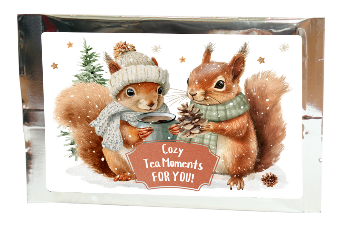 Tea greeting card in silver packaging with two squirrels in winter clothing and the message “Cozy Tea Moments FOR YOU!”