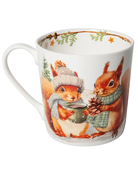 White mug with the handle on the left, showing two squirrels in winter scarves holding a green cup and a pine cone.