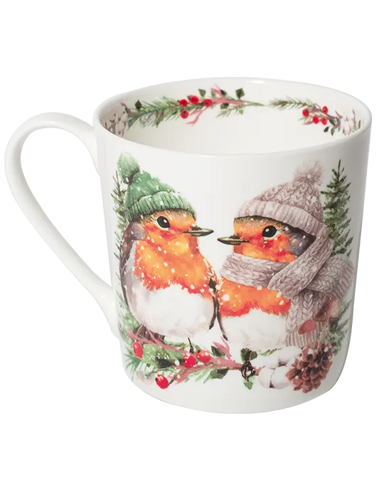 White mug with the handle on the left, featuring two robins in green and mauve winter hats perched on a snowy branch with red berries.