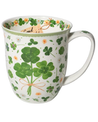 White mug with green four-leaf clovers tied in a bouquet, small flowers, and a pale green rim.