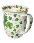 White mug with green four-leaf clovers tied in a bouquet, small flowers, and a pale green rim.