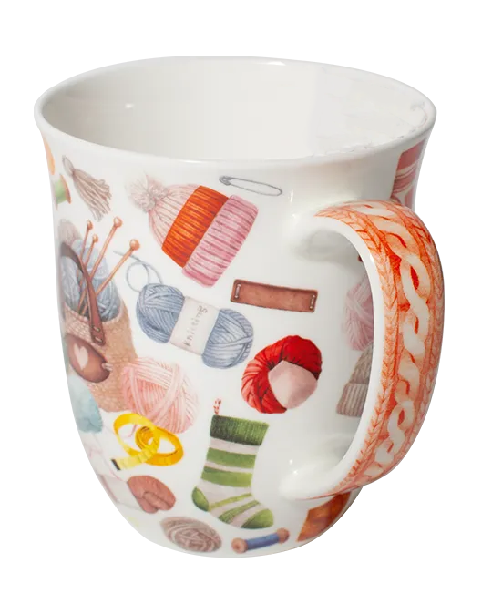 White mug decorated with colourful balls of yarn, knitting needles, and a knitting bag with a heart detail.