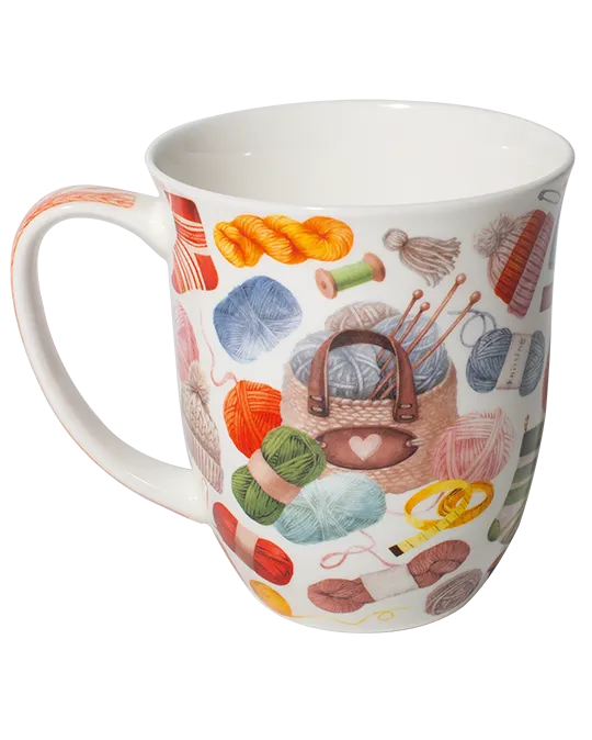White mug decorated with colourful balls of yarn, knitting needles, and a knitting bag with a heart detail.
