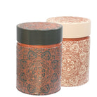 Two cylindrical containers with decorative patterns on a dark and beige background
