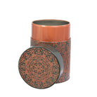 Decorative cylindrical container with mandala design on a dark background