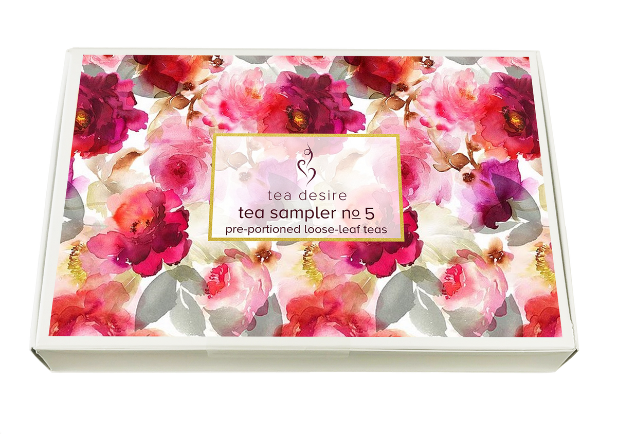 A rectangular box of 'tea desire tea sampler no 5' pre-portioned loose-leaf teas, featuring a vibrant watercolor floral pattern in pink, red, and purple tones with a central gold-bordered label.