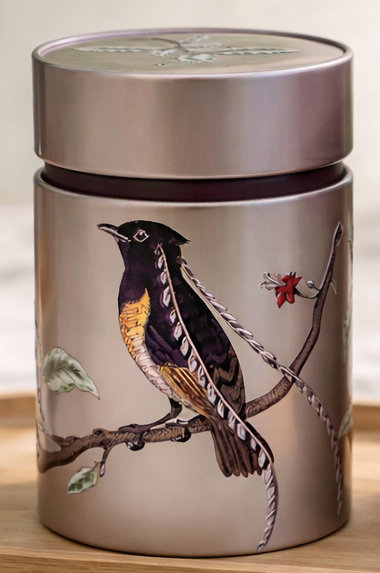 Silver cylindrical container with a bird illustration on a branch