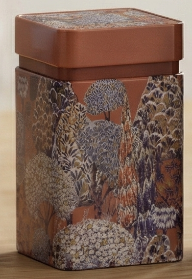 Decorative tin box with floral pattern on a brown metal surface