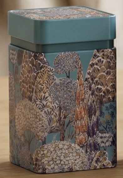Decorative tin box with a tree pattern on a petrol coloured metal surface
