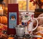 Autumn Coziness Gift Pack with Vanilla Chai tea, horse mug, mesh infuser and measuring spoon among pumpkins and autumn leaves.